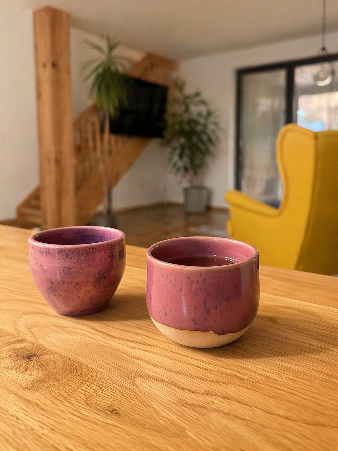 Dva růžové keramické kalíšky na dřevěném stole